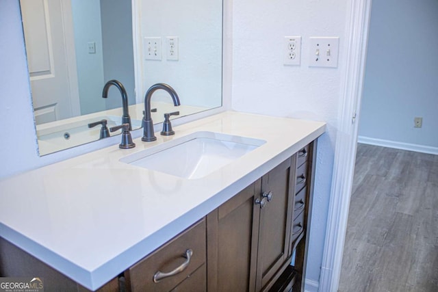 bathroom with vanity, wood finished floors, and baseboards