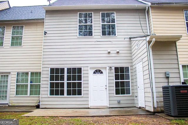 exterior space featuring a patio area, central AC unit, and a shingled roof