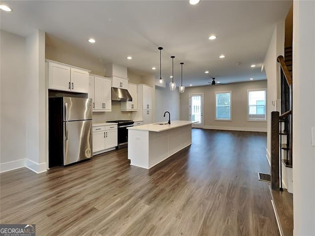 kitchen with a ceiling fan, electric stove, under cabinet range hood, open floor plan, and freestanding refrigerator