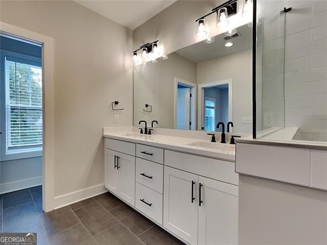 full bath with visible vents, baseboards, double vanity, tile patterned floors, and a sink