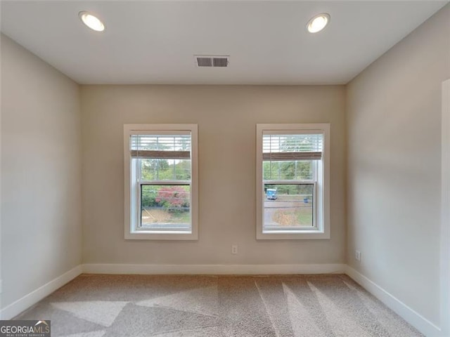 unfurnished room featuring visible vents, baseboards, light colored carpet, and a healthy amount of sunlight