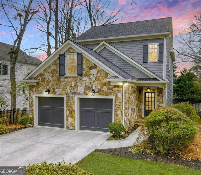 view of front of property featuring concrete driveway, fence, a garage, and stone siding