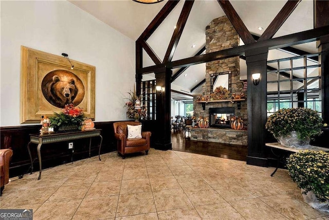 living area featuring tile patterned flooring, beamed ceiling, a fireplace, and high vaulted ceiling