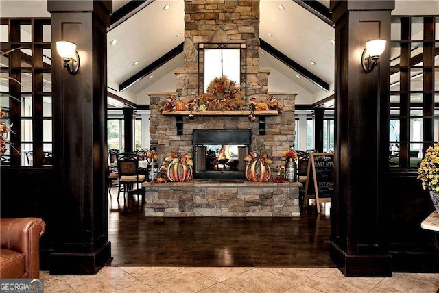 tiled living area featuring a stone fireplace, beamed ceiling, and high vaulted ceiling