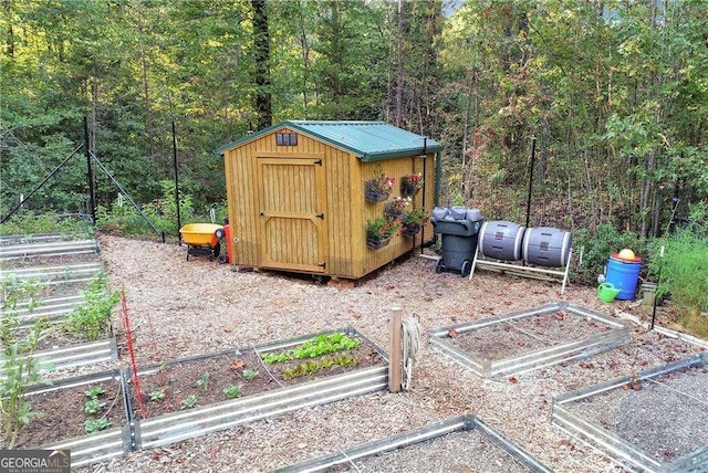 view of shed with a vegetable garden and a forest view