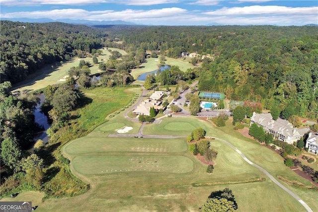 drone / aerial view featuring view of golf course and a view of trees