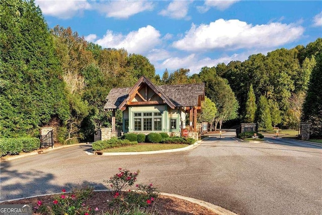 tudor-style house with a gate, fence, and a wooded view