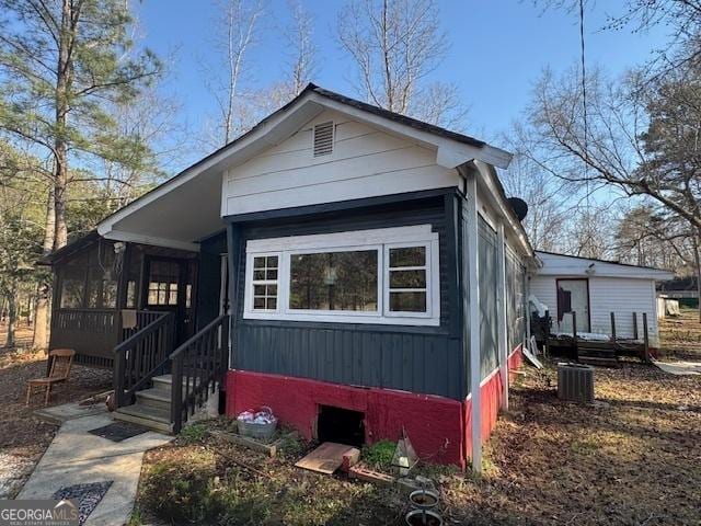 view of front of house with central air condition unit and a sunroom