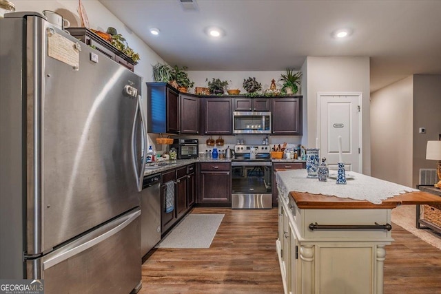 kitchen featuring stainless steel appliances, a kitchen island, dark brown cabinets, and dark wood-style floors