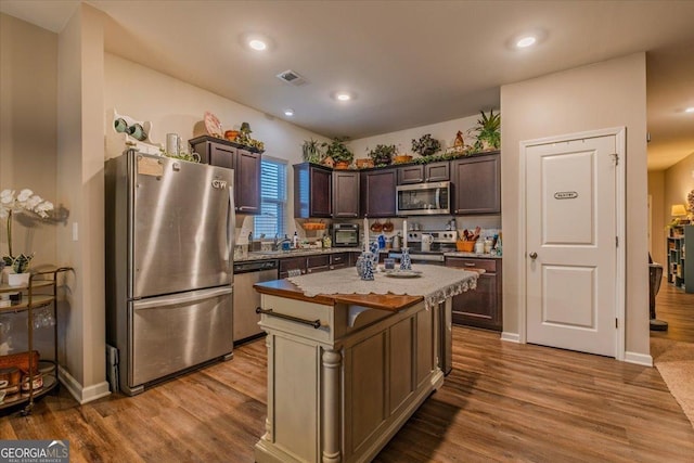 kitchen featuring visible vents, dark brown cabinetry, appliances with stainless steel finishes, and wood finished floors