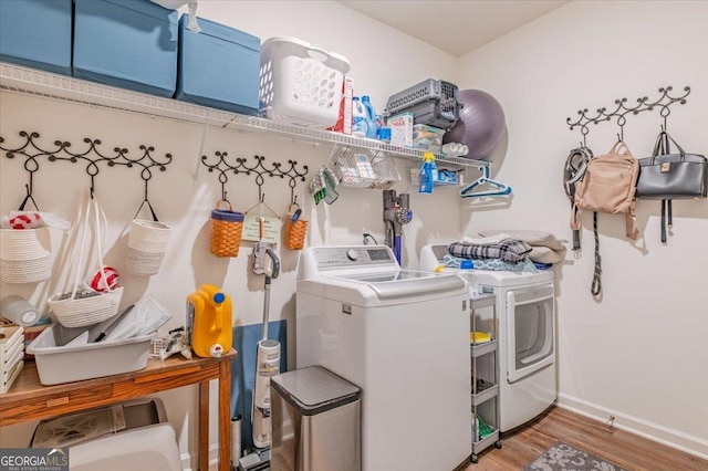 washroom featuring baseboards, separate washer and dryer, wood finished floors, and laundry area