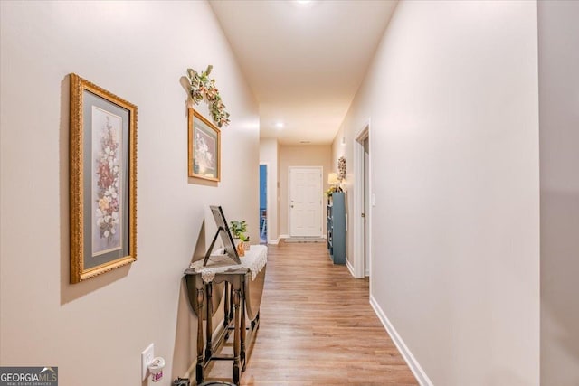 hallway featuring baseboards and light wood-style floors