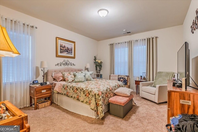 bedroom featuring visible vents and light colored carpet