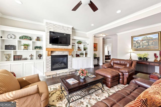 living area with wood finished floors, ceiling fan, a fireplace, and ornamental molding