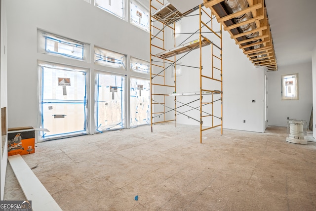 unfurnished living room featuring a towering ceiling