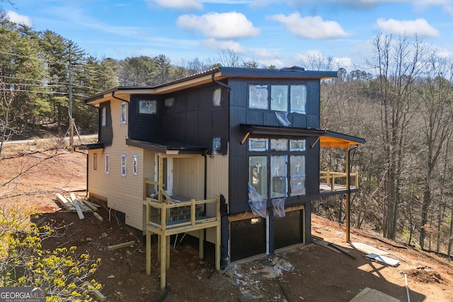 back of property featuring a deck, a garage, and driveway