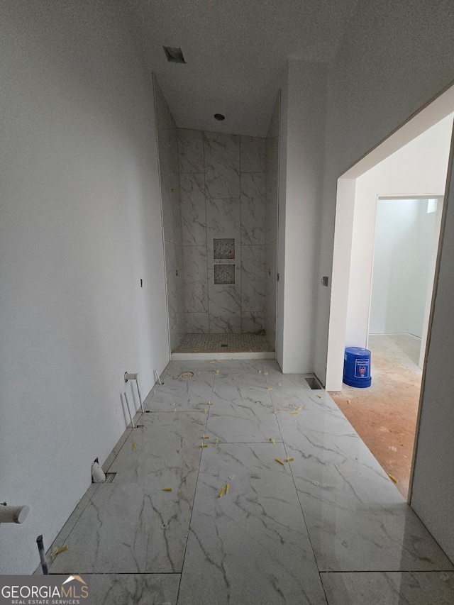 bathroom with visible vents, marble finish floor, and a tile shower