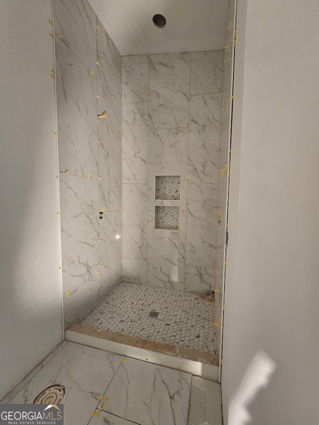 bathroom with marble finish floor and a stall shower