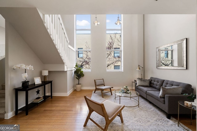 living room with stairs, light wood-style flooring, and baseboards