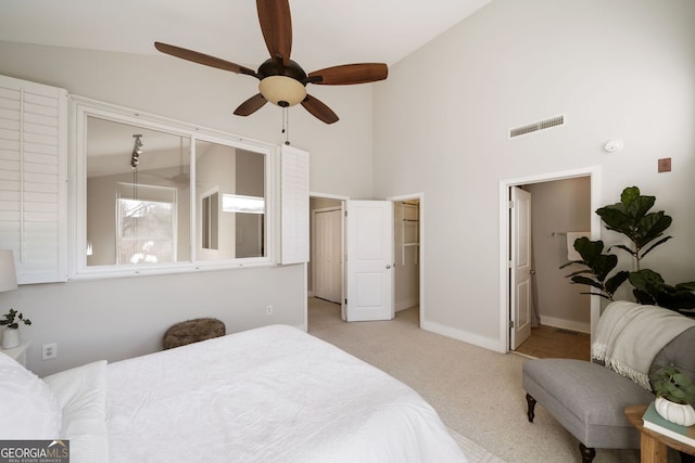 bedroom featuring visible vents, baseboards, light colored carpet, high vaulted ceiling, and ensuite bath