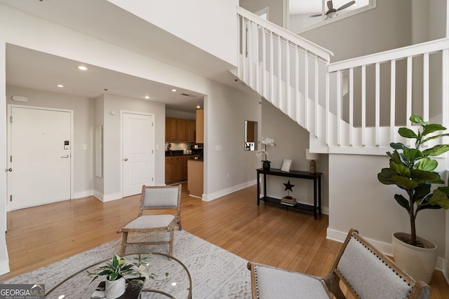 sitting room featuring stairs, baseboards, and light wood-type flooring