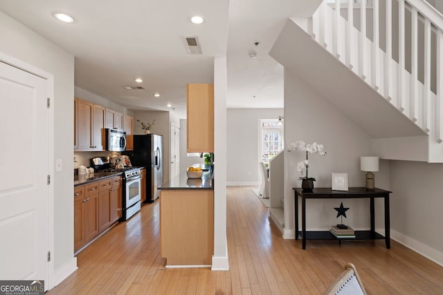 kitchen with light wood-type flooring, visible vents, dark countertops, and appliances with stainless steel finishes