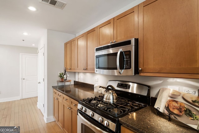 kitchen with visible vents, recessed lighting, dark stone countertops, light wood-style flooring, and stainless steel appliances