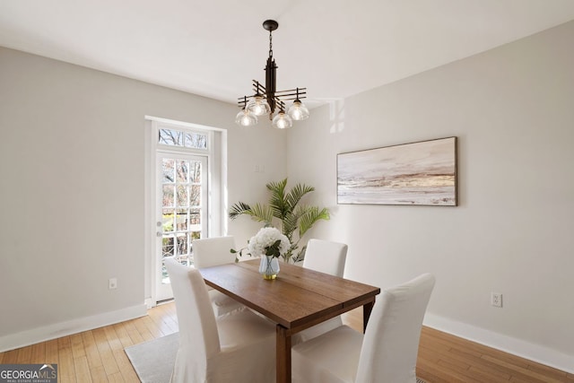 dining room with an inviting chandelier, baseboards, and light wood finished floors