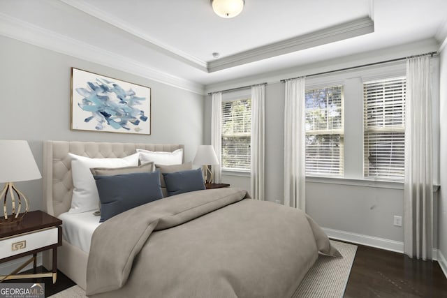 bedroom with crown molding, a raised ceiling, baseboards, and wood finished floors