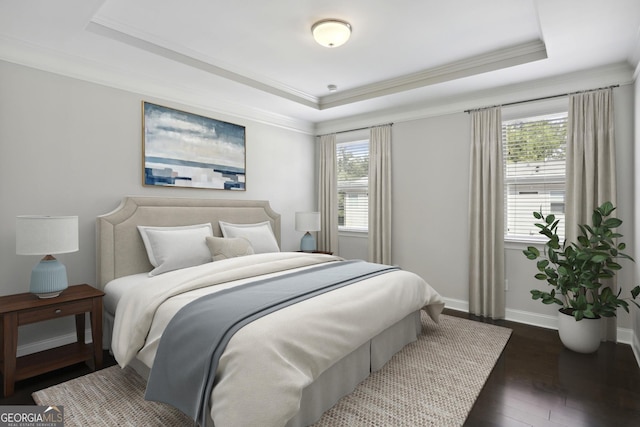 bedroom featuring dark wood finished floors, a raised ceiling, multiple windows, and baseboards