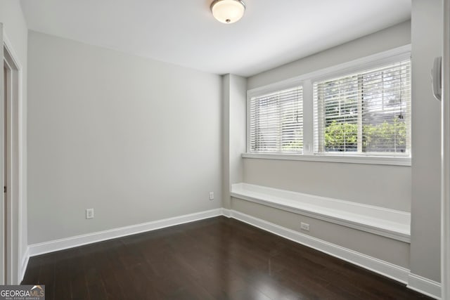 spare room featuring baseboards and dark wood-type flooring