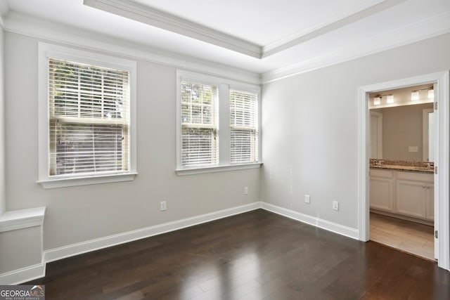 unfurnished bedroom featuring dark wood-style floors, ensuite bath, crown molding, and baseboards