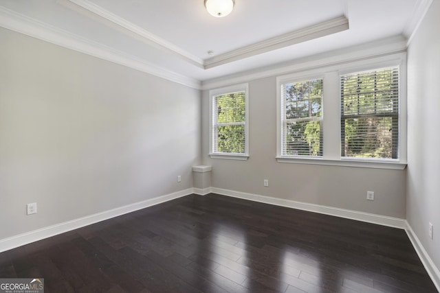 empty room featuring a tray ceiling, crown molding, dark wood-style floors, and baseboards