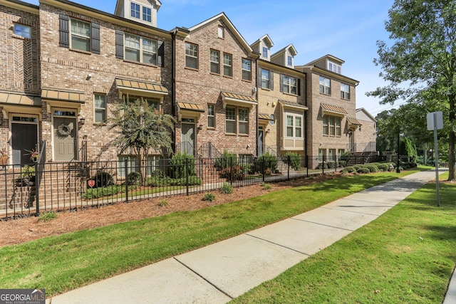 view of property featuring a fenced front yard, a residential view, and brick siding