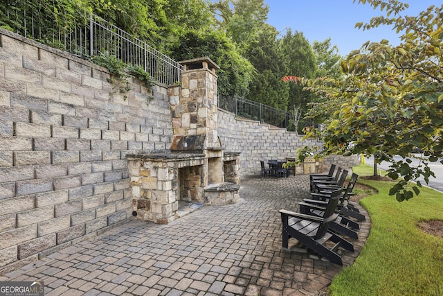 view of patio with an outdoor stone fireplace and fence