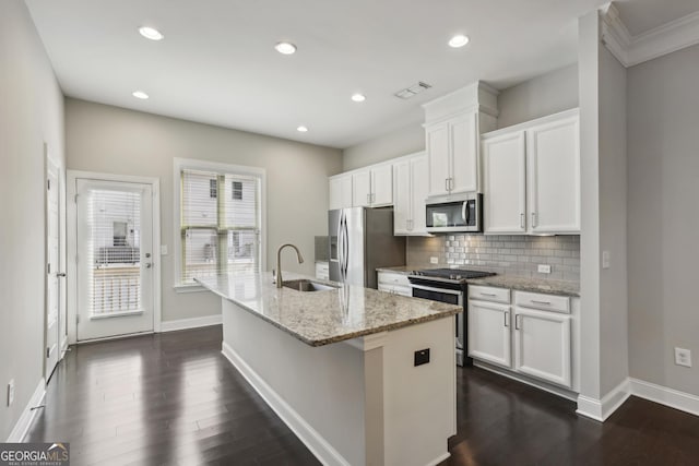 kitchen with visible vents, an island with sink, a sink, appliances with stainless steel finishes, and tasteful backsplash