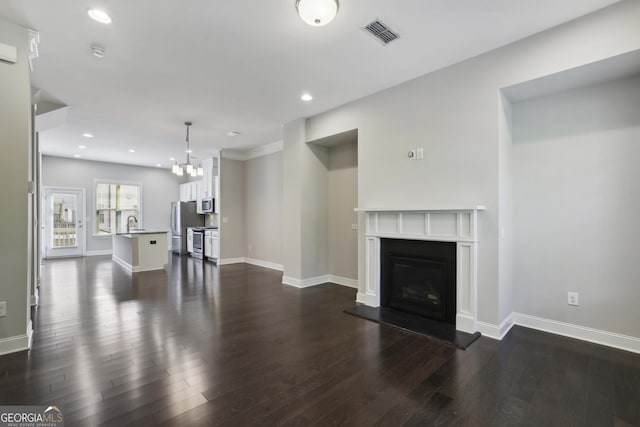 living area with dark wood-style floors, visible vents, baseboards, recessed lighting, and a glass covered fireplace