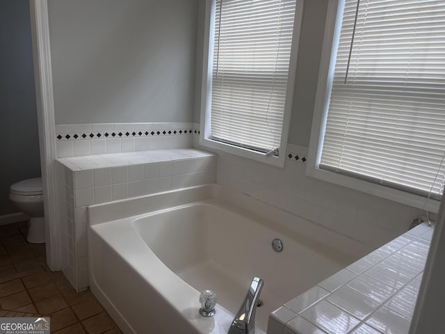 bathroom with toilet, a bath, and tile patterned flooring