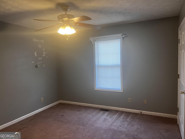 spare room with a ceiling fan, baseboards, a textured ceiling, and dark carpet