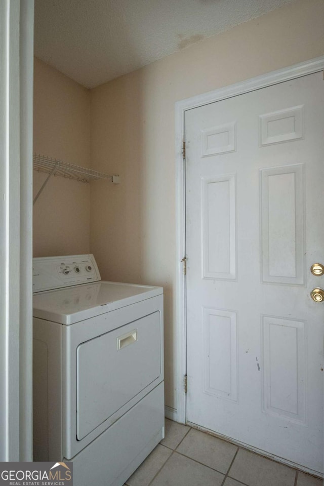 clothes washing area featuring light tile patterned floors, laundry area, and washer / clothes dryer