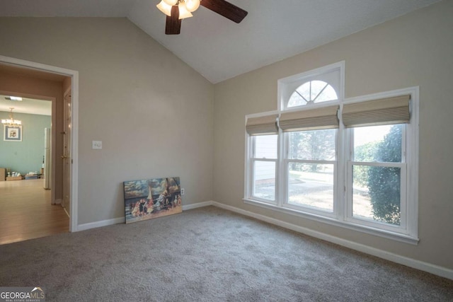 carpeted spare room featuring lofted ceiling, ceiling fan with notable chandelier, and baseboards