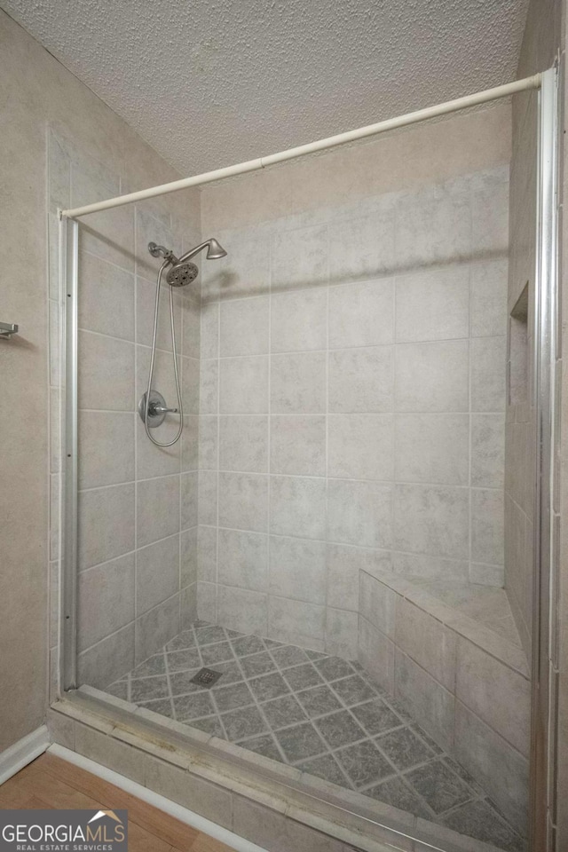 full bathroom with a shower stall and a textured ceiling