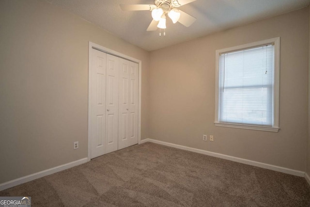 unfurnished bedroom with a closet, baseboards, carpet, and a ceiling fan