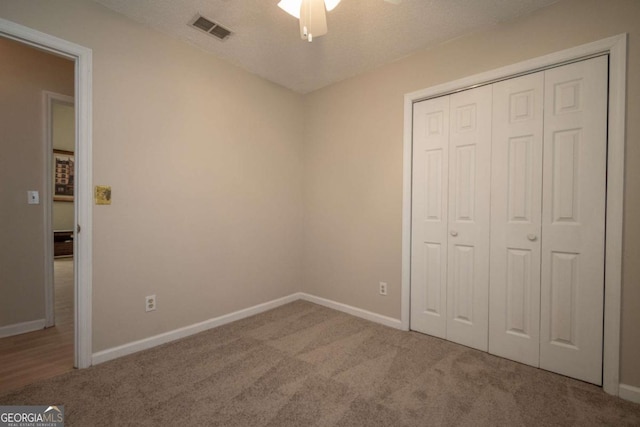 unfurnished bedroom featuring baseboards, visible vents, carpet floors, ceiling fan, and a closet