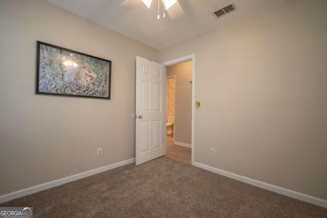 unfurnished bedroom featuring visible vents, a ceiling fan, a textured ceiling, carpet floors, and baseboards