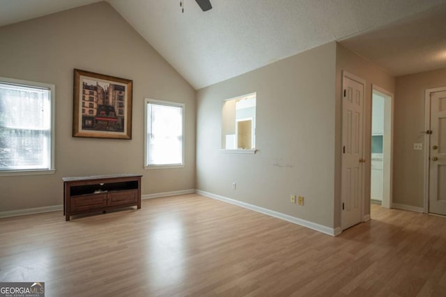 interior space with lofted ceiling, baseboards, light wood-type flooring, and ceiling fan