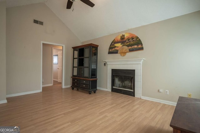 unfurnished living room featuring a tiled fireplace, visible vents, ceiling fan, and wood finished floors