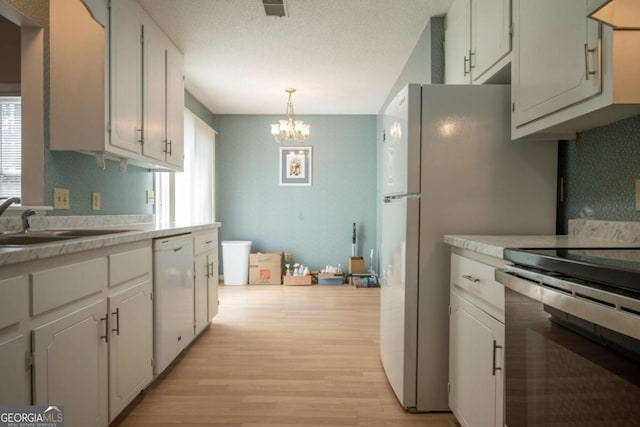 kitchen with stainless steel electric stove, ventilation hood, white dishwasher, light countertops, and a chandelier