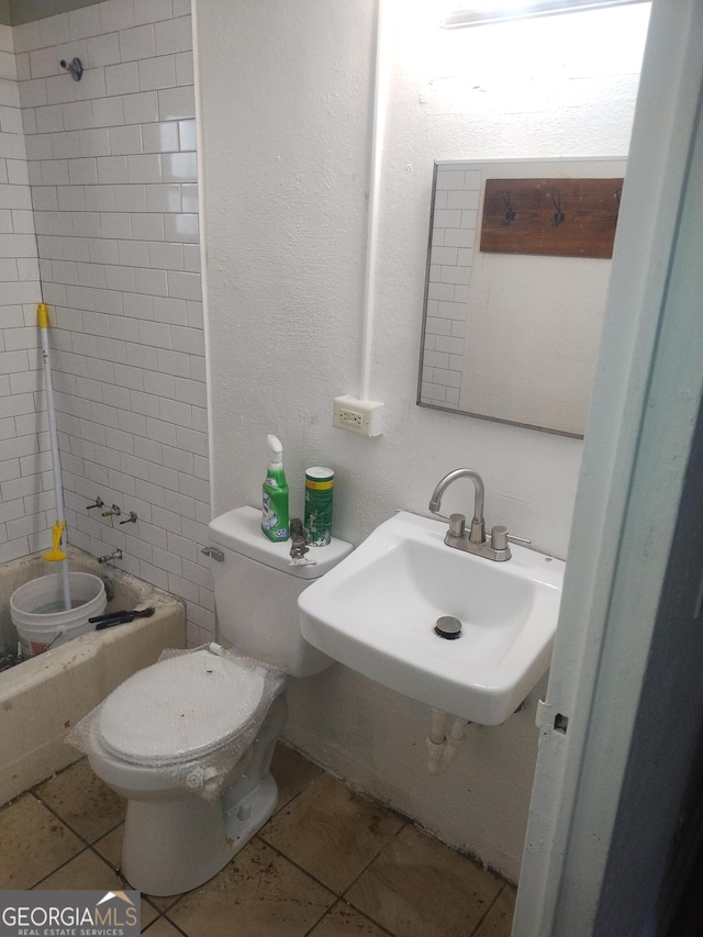 full bath featuring a sink, toilet, tile patterned flooring, and a textured wall