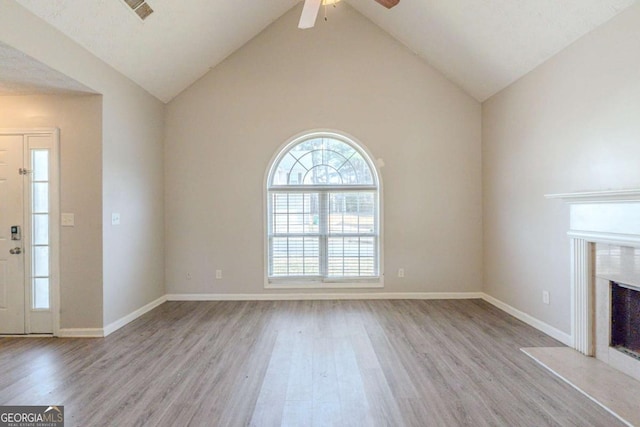 unfurnished living room featuring baseboards, wood finished floors, ceiling fan, and a fireplace